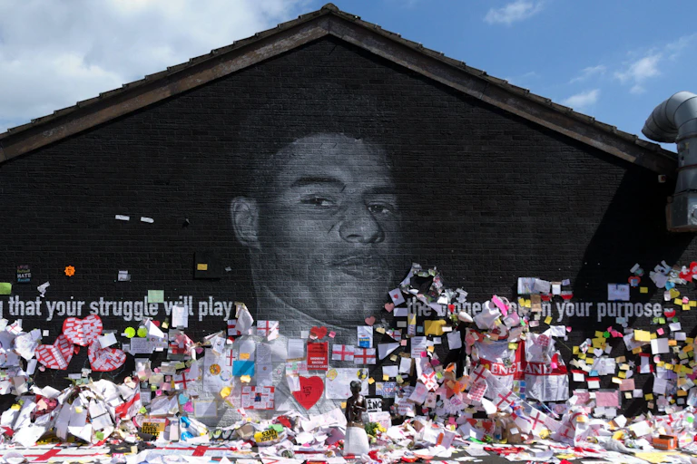 Mural of Marcus Rashford covered with notes, pictures and flags.
