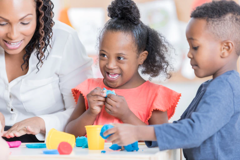 A two children play with Play-Doh with a woman.