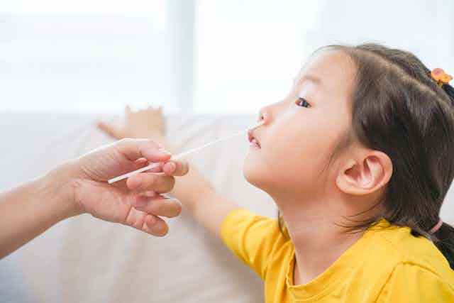 Child getting a nasal swab by adult for COVID test