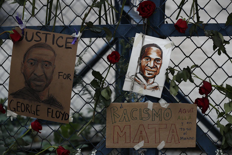 A painted picture of George Floyd is seen on a fence surrounded by roses.