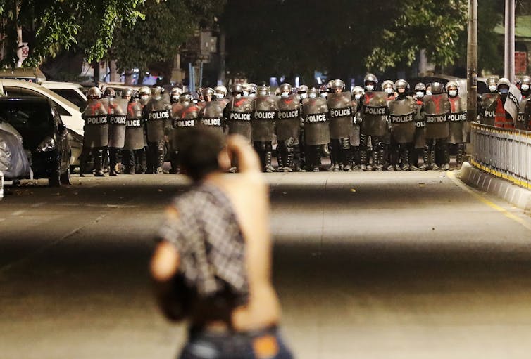 A demonstrator gestures at anti-riot police.