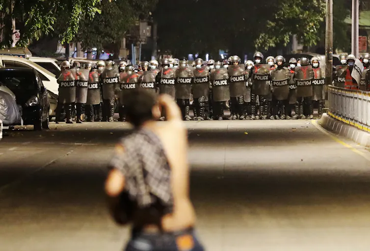 A demonstrator gestures at anti-riot police.