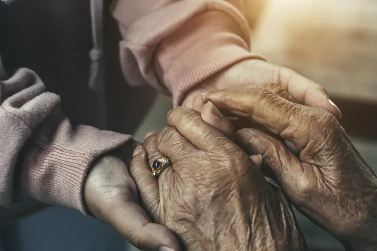Older hands clasping younger hands