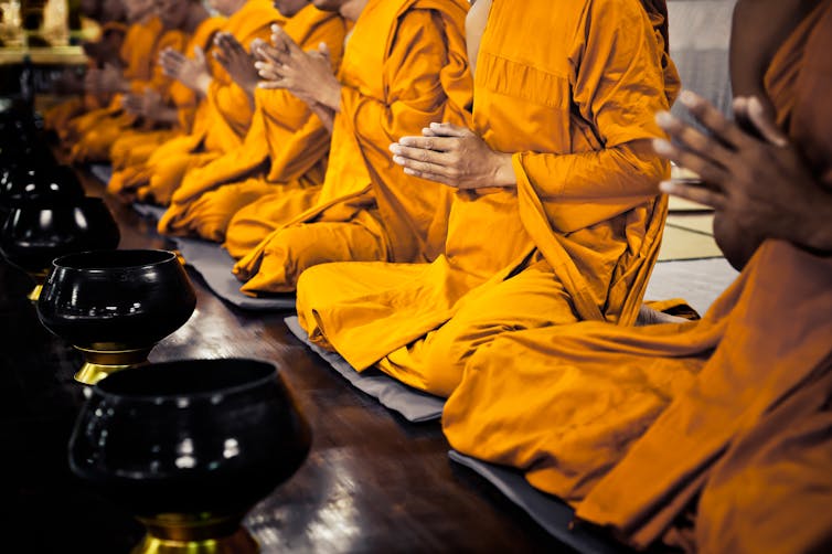 Buddhist monks in orange robes praying