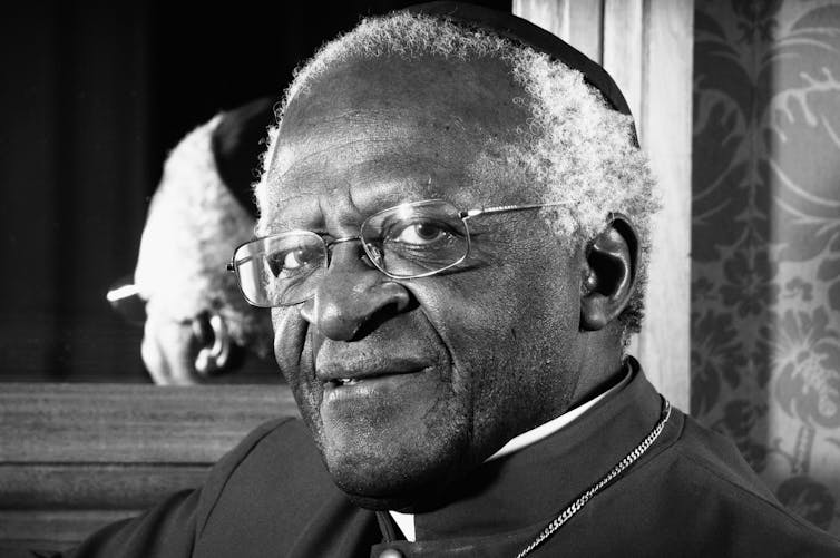A Black man poses in front of a mirror.