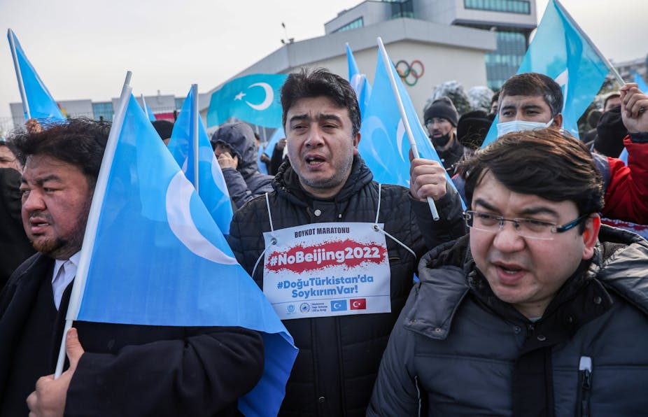 Men holding blue flags with sign saying 'no Beijing 2022'