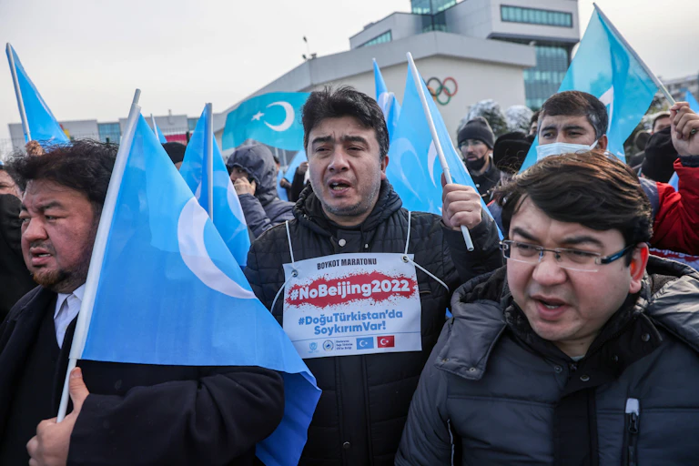 Men holding blue flags with sign saying 'no Beijing 2022'