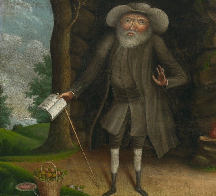 A portrait of man with a white beard, wearing a hat and a long coat.