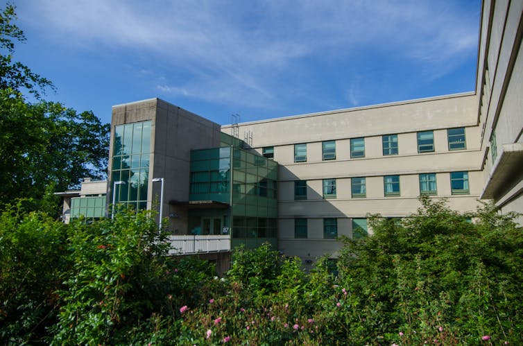 An exterior view of a hospital with a lush garden outside.