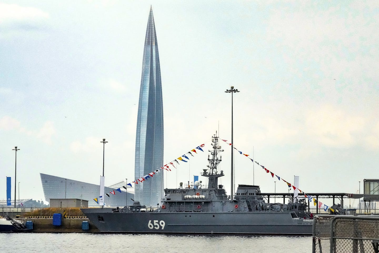 A tall pointed skyscraper with battleship in foreground.