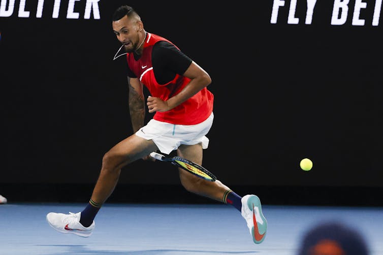 Nick Kyrgios plays a shot back between his legs.