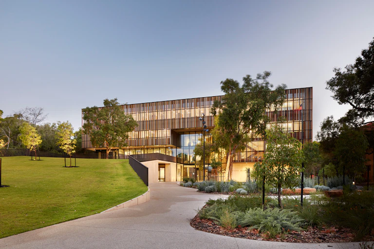 The entrance to a large glass building surrounded by trees.