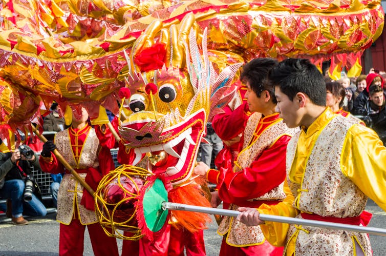 Dragon puppet being made to dance by men.