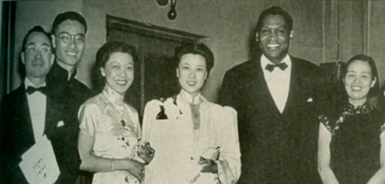 Black and white photo of people dressed in formal attire in a row at a banquet.