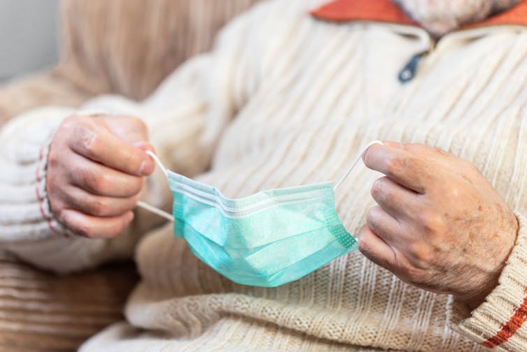 An older man putting on a face mask