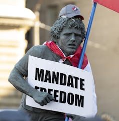 A statue of Terry Fox with a sign that says mandate freedom.