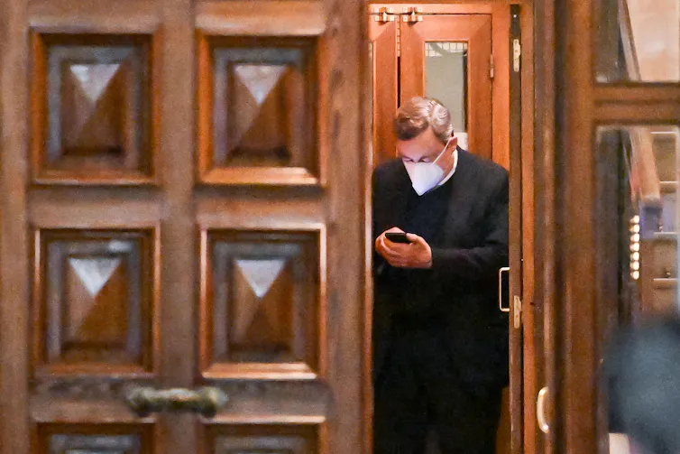 Mario Draghi looking at a phone at the building where he lives