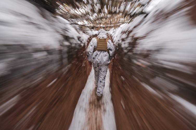 A serviceman walks in a trench