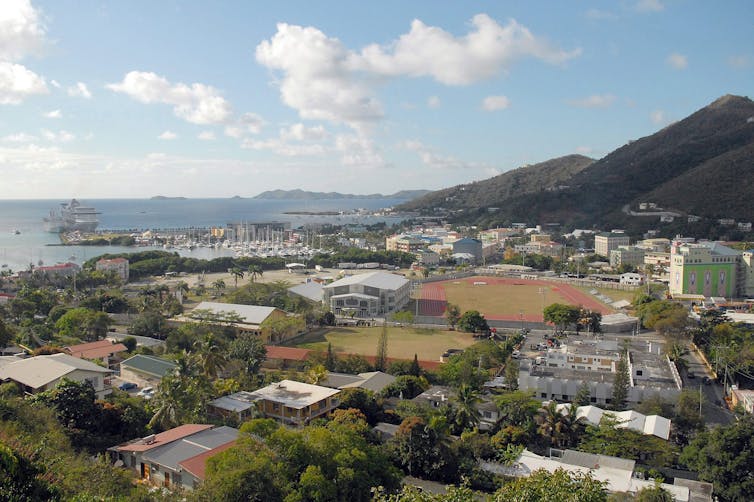 A town is seen with mountains and the ocean in the background.