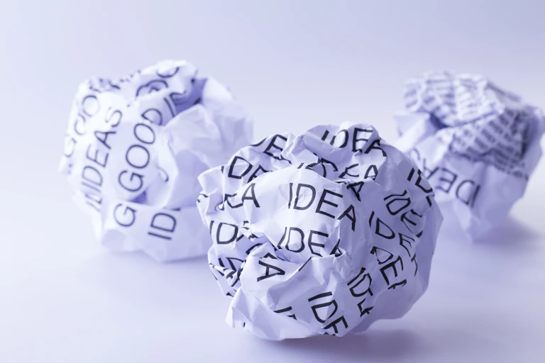 Scrunched up balls of paper with words 'good ideas' printed on them