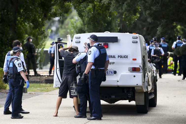 Police are arresting a person, loading them into a paddywagon.