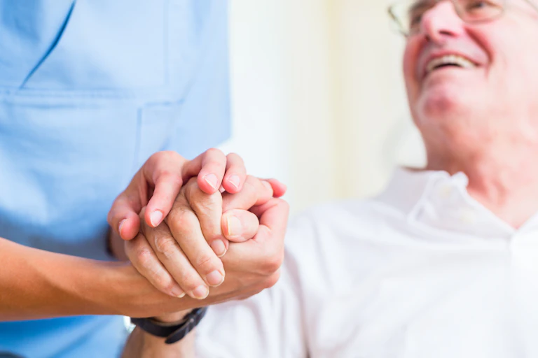 older man holds carer's hand