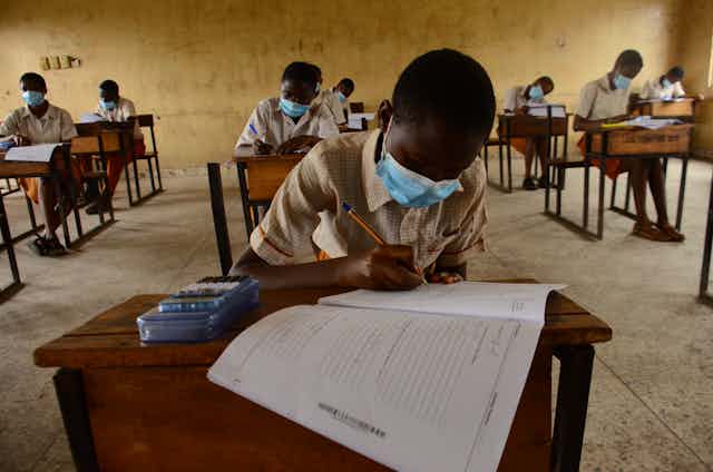 Final year students of Agidinbi Senior Grammar School,Ikeja, Lagos, wearing a facemask write on examination answer sheets.