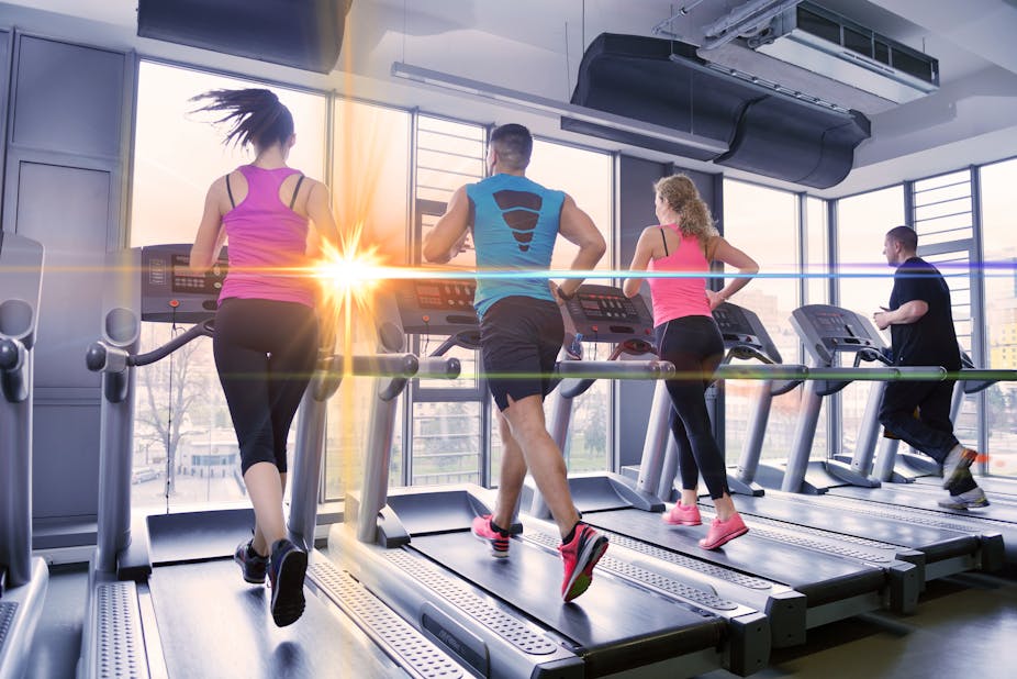 Four people running on different treadmills next to each other in the gym.
