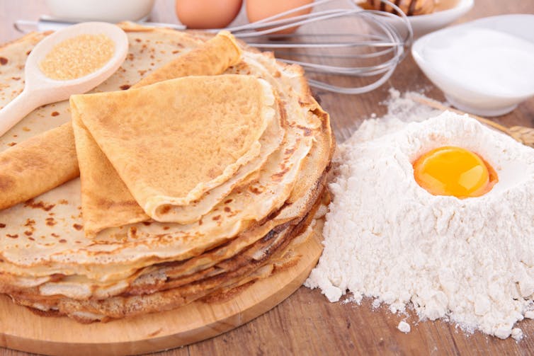 Crêpes natures à côté des ingrédients de base : farine, œufs, etc.