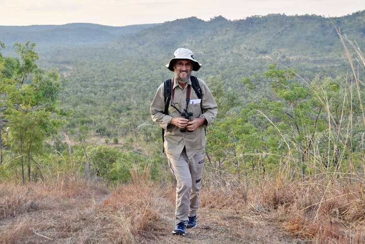 Man on bushwalk holding binoculars