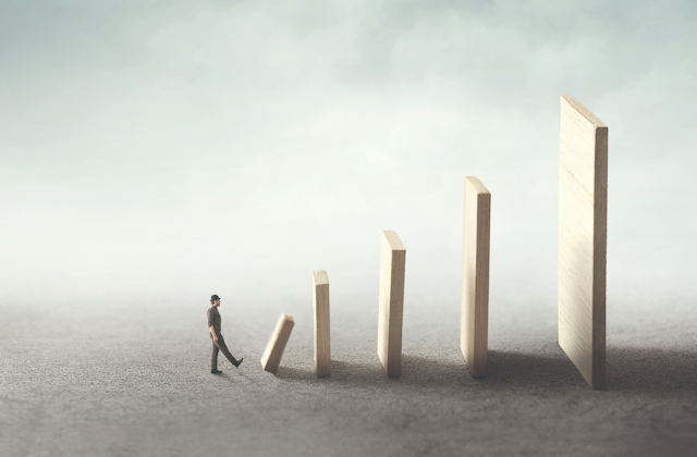 Illustration of a person kicking over a monolith, which in turn will knock over a series of increasingly larger monoliths behind it