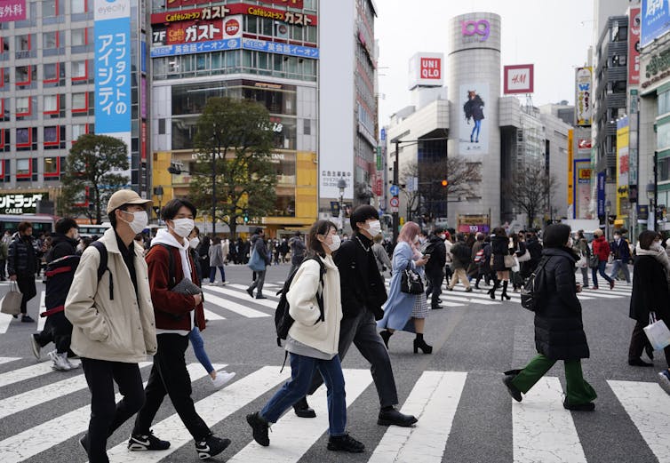 जापानी शहर में सड़क पार करते लोग