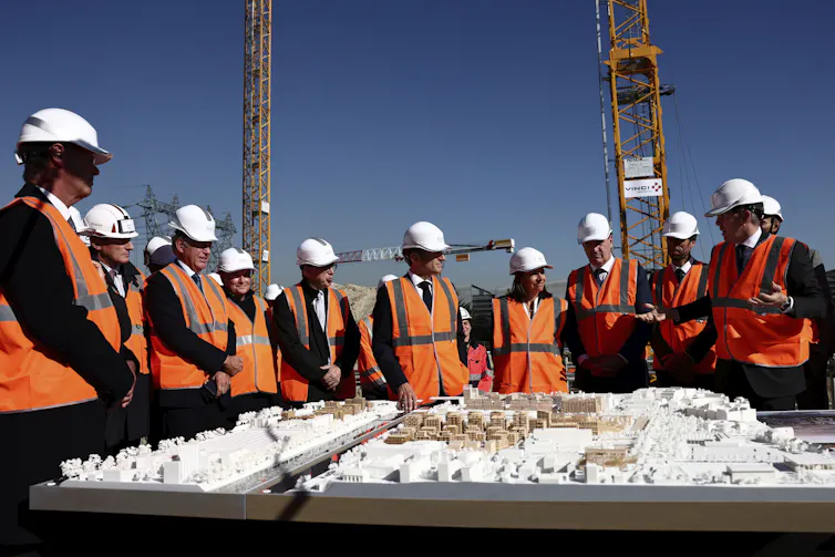 Un groupe de personnes avec des casques de construction observent une maquette