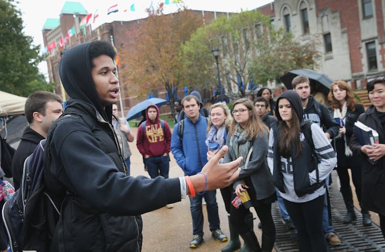 young black man speaks to crowd of young adults