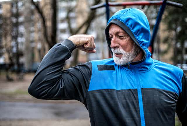 An older man flexing his arm.