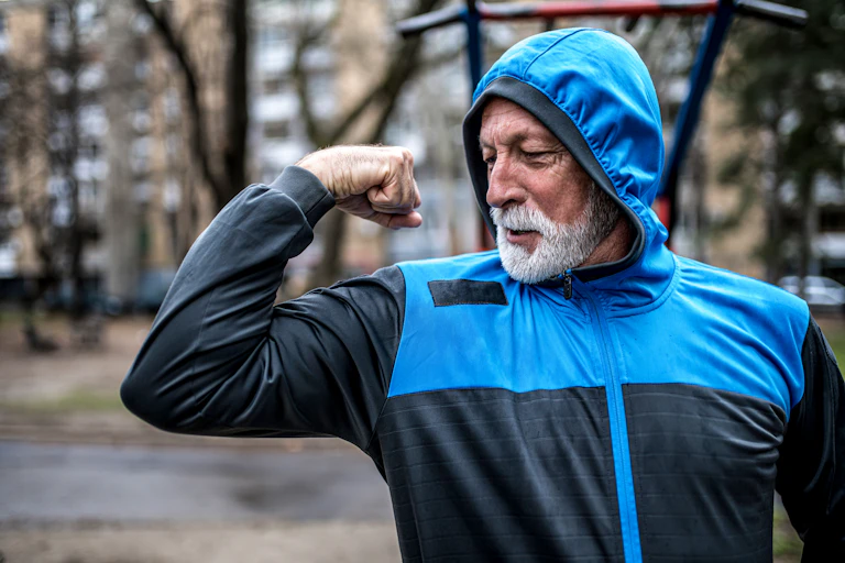 An older man flexing his arm.