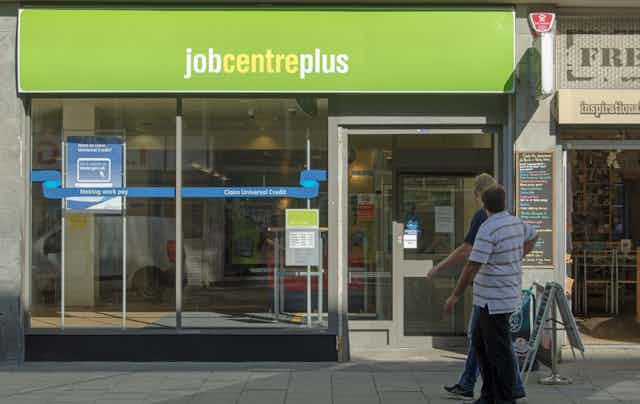 Two men walking in front of a JobCentrePlus shopfront