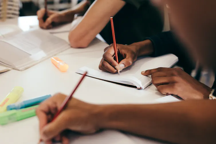 People hands are seen writing in notebooks.