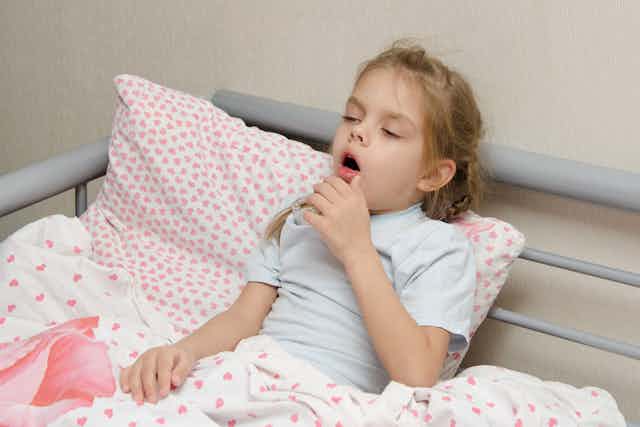 Child in bed coughing.