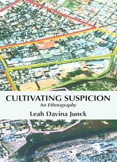 A book cover showing the title and author - Cultivating Suspicion: An Ethnography by Leah Davina Junck - and an illustration of an aerial view of a suburban area, colourised.