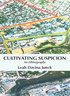 Langaa RPCIG A book cover showing the title and author - Cultivating Suspicion: An Ethnography by Leah Davina Junck - and an illustration of an aerial view of a suburban area, colourised.
