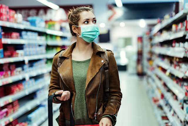 A woman wearing a face mask in a supermarket shopping