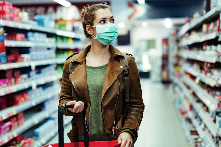 A woman wearing a face mask in a supermarket shopping