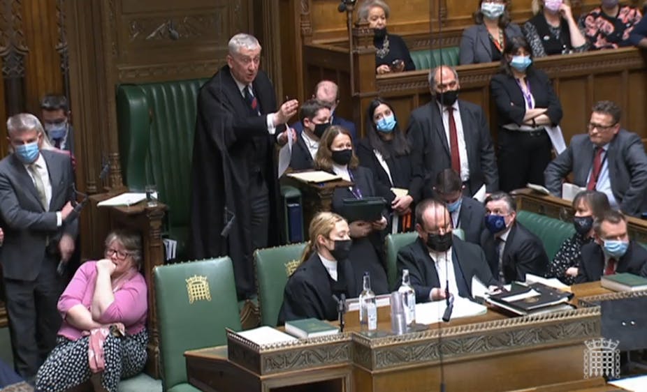 Speaker of the House of Commons Sir Lindsay Hoyle gestures in front of a packed chamber.