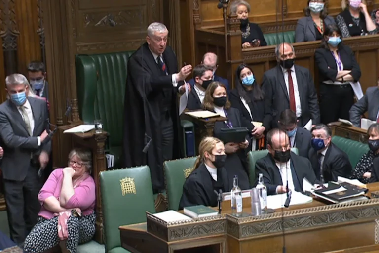 Speaker of the House of Commons Sir Lindsay Hoyle gestures in front of a packed chamber.