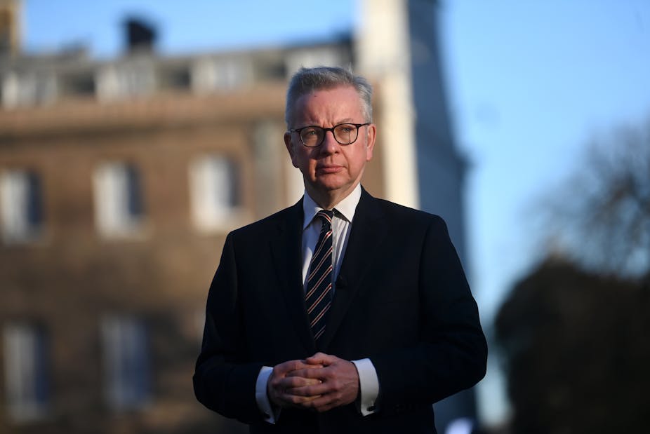Michael Gove looking pensive in front of  abuilding