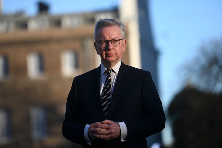 Michael Gove looking pensive in front of abuilding