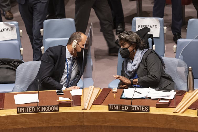 UK Ambassador James Kariuki and U.S. Ambassador Linda Thomas-Greenfield lean towards each other across a table during a U.N. Security Council meeting on Ukraine on Jan. 21, 2022.