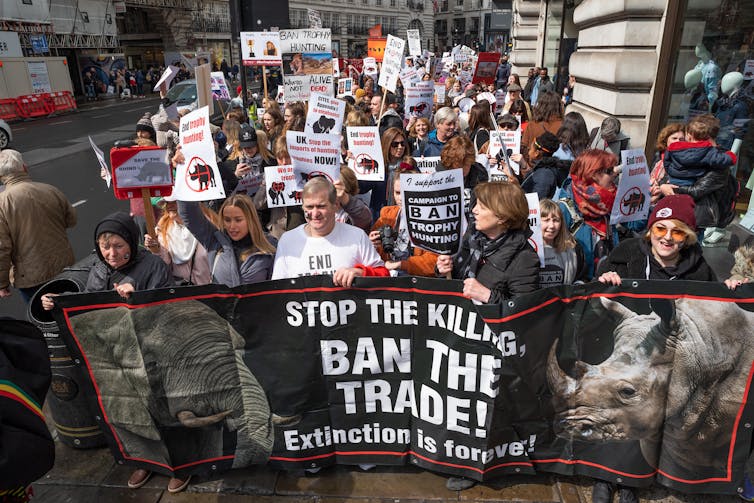 People marching through London carrying banners against Trophy Hunting and Extinction