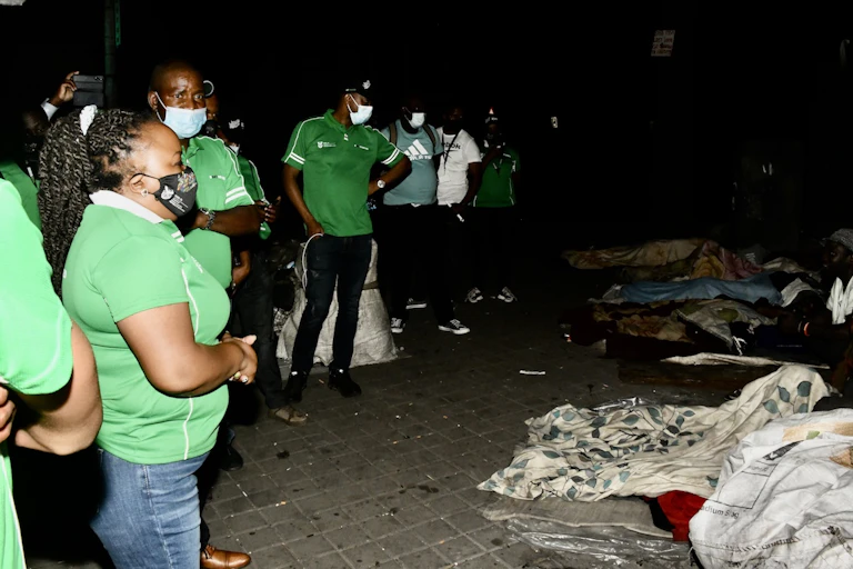 Men and women look in disbelief at several homeless people sleeping in the open in Johannesburg.